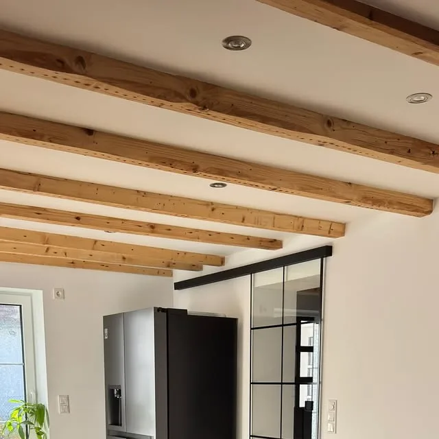 Sanierter Wohnraum mit sichtbaren Holzbalken und moderner Küche