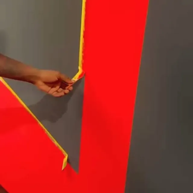 Maler klebt eine rote Wand für den Endanstrich ab